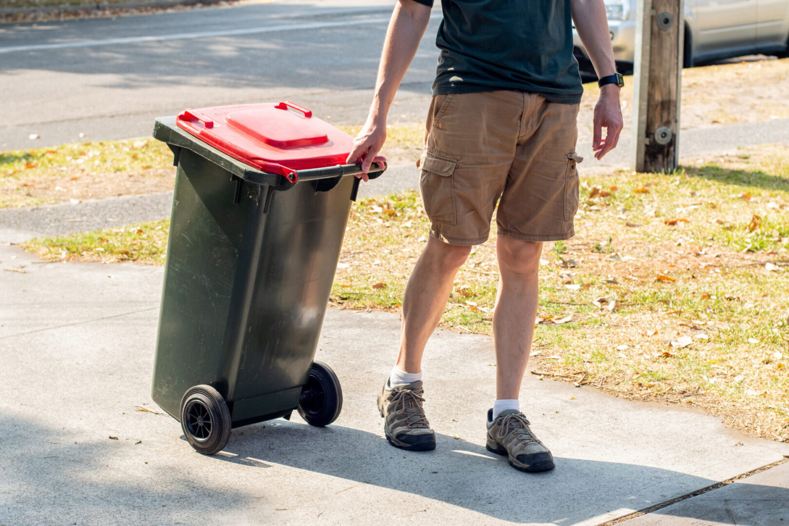 A man is walking with his trash can