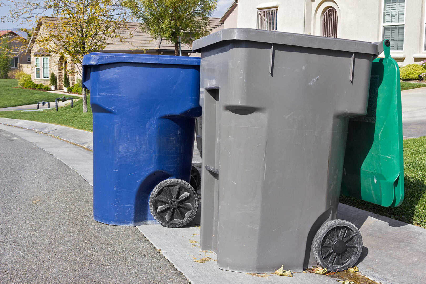 Two garbage cans are sitting on the side of a street.